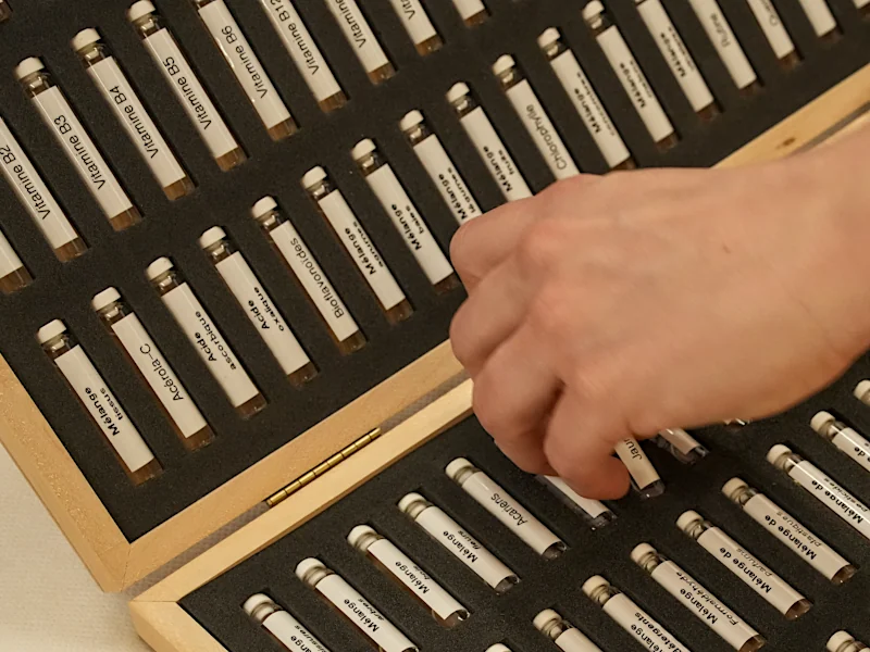 Eine Hand greift nach Reihen kleiner Fläschchen, die Allergene enthalten