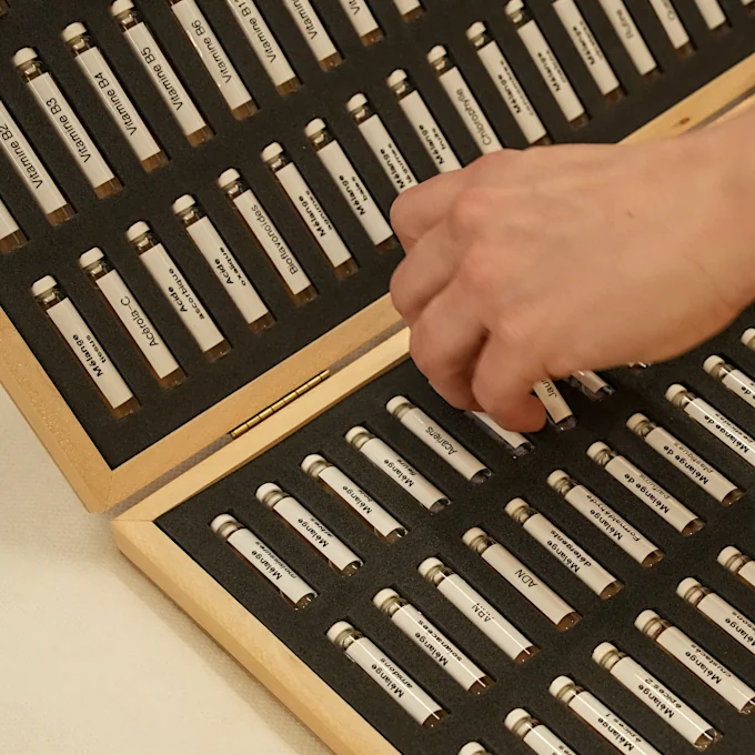 Eine Hand greift nach Reihen kleiner Fläschchen, die Allergene enthalten